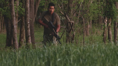 a man with a rifle moving cautiously through a forest in collierville, tennessee, usa