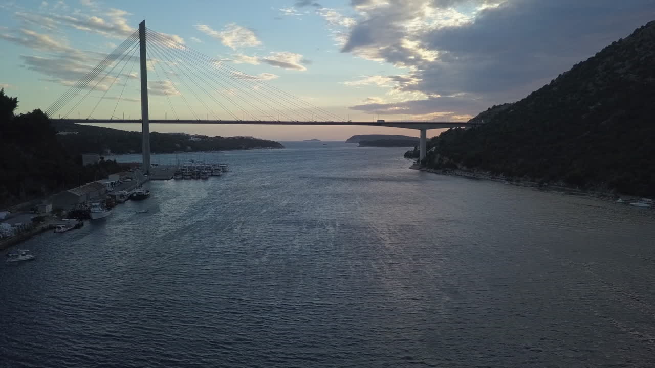 Silhouette of tall bridge over windy Dubrovnik inner harbour at dusk