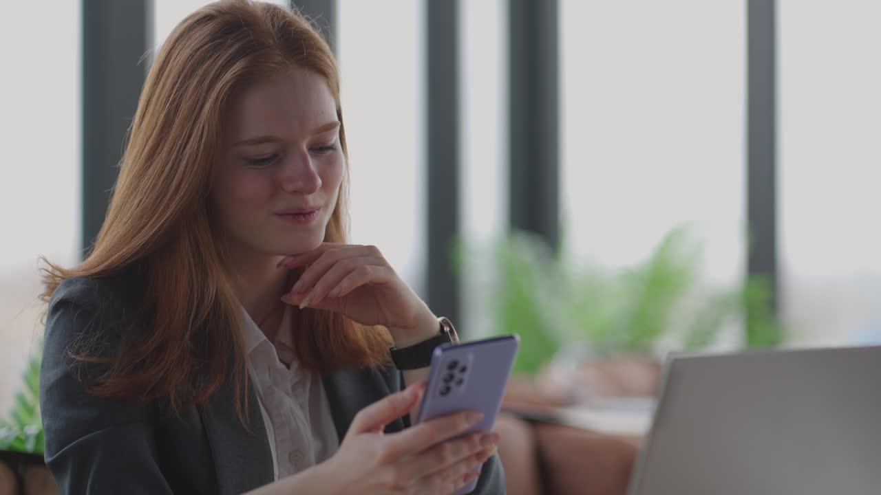 mujer de negocios en una oficina moderna con una ventana panorámica día soleado tableta portátil uso de un teléfono móvil en una situación