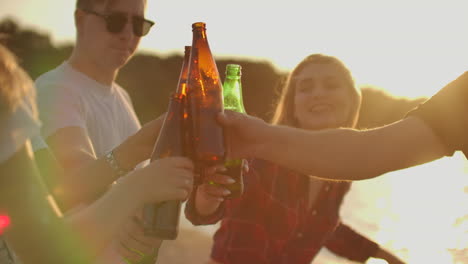 company of young people celebrate the end of the semester with beer. this is carefree summertime. they clink and drink beer on the open air party.