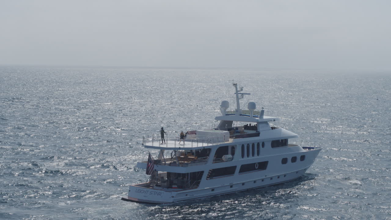 Ripresa aerea con drone in avvicinamento di uno yacht che naviga nel profondo mare blu in una giornata di sole
