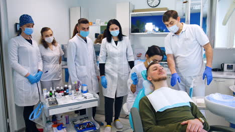 dental cabinet full of students of dentistry course. future medics are practicing on a patient.