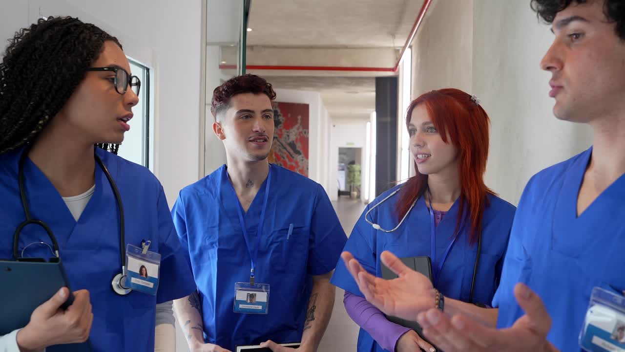 Jóvenes profesionales médicos con uniformes hablando en el pasillo del hospital.