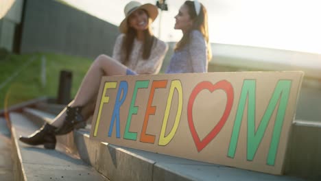 video di un cartellone colorato e due donne sullo sfondo