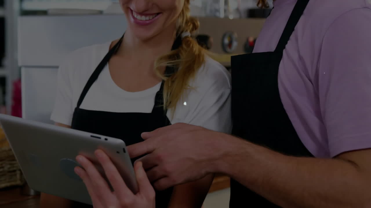 Animation of network of connections with icons over caucasian man and woman using tablet