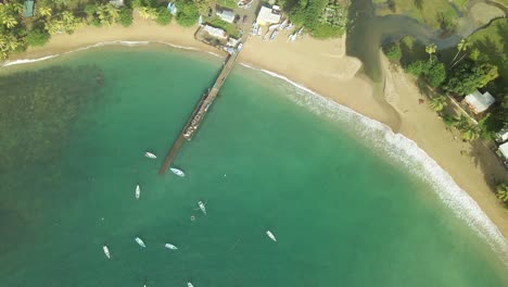 Aufsteigender-Luftraketenblick-Auf-Den-Parlatuvier-Strand-Und-Die-Anlegestelle-Mit-Fischerbooten,-Die-In-Ihrem-Blauen-Wasser-Verankert-Sind