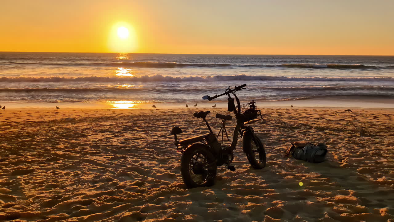 바다 위의 배경에서 해가 지는 해변에 있는 전기 자전거