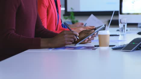 Side-view-of-mixed-race-business-colleagues-discussing-over-digital-tablet-in-modern-office-4k