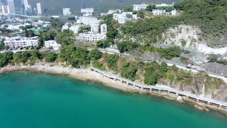 Hong-Kong-bay-coastal-road-with-traffic-and-calm-turquoise-water,-Aerial-view