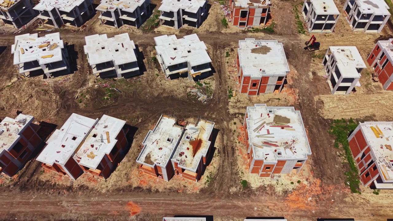 Obra en construcción con edificios sin terminar dispersos por el paisaje durante el día en una zona urbana