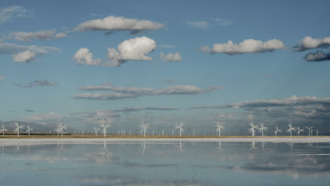 wind turbines spin near the water under a blue sky