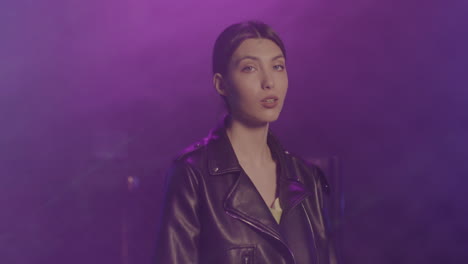 beautiful girl in leather jacket looking confidently at camera at disco