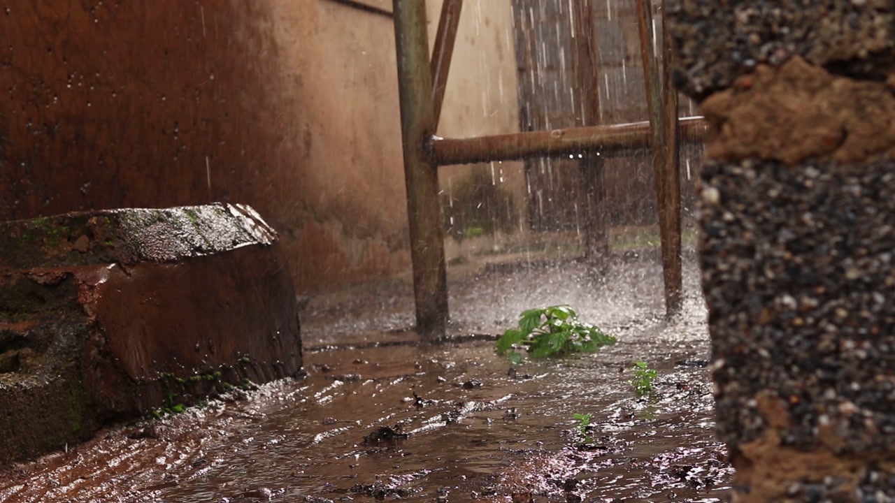 Water flowing from a water tower falling on the streets of an alley in a rural Nigerian village