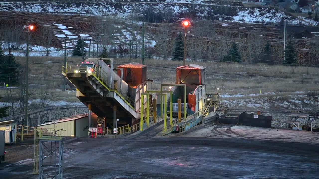 A Close-Up Aerial View of a Semi Truck Discharging Wood Products at a Sawmill via a Back-on Truck Dumper in British Columbia, Canada