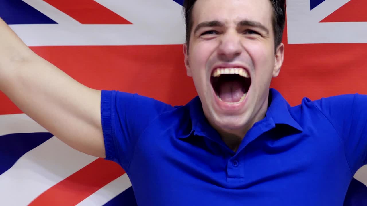 영국 젊은이가 영국 발을 느린 동작으로 들고 축하합니다.