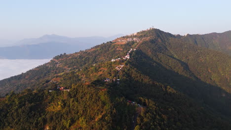 aerial view circling the sunlit sarangkot mountain, foggy morning in nepal