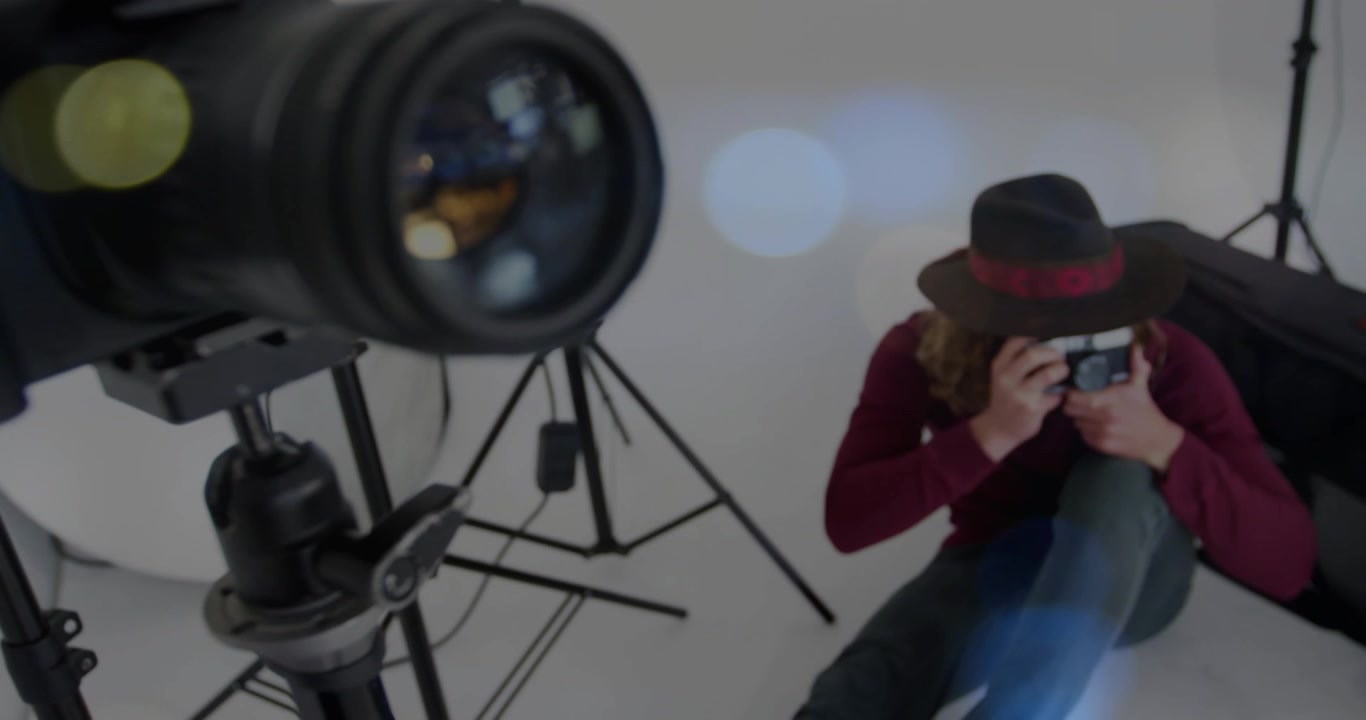 Professionista della fotografia che solleva una macchina fotografica a pellicola, inquadrando con un teleobiettivo da diverse angolazioni su sfondo bianco.