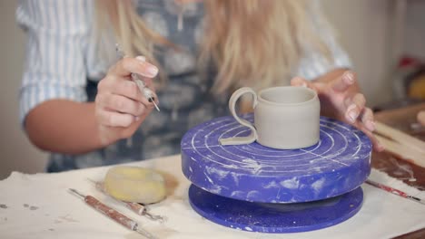 mujer formando una taza de arcilla en una rueda de cerámica