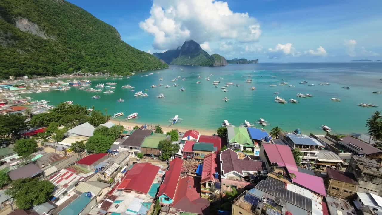 This stunning aerial photograph captures the vibrant coastal town and the beach of El Nido, Palawan. Scattered with fluffy white clouds, adds a sense of tranquility to this tropical paradise.