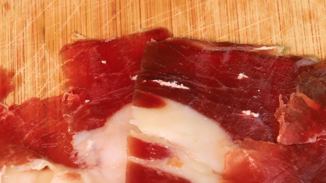 lonchas de prosciutto graso girando sobre una tabla de madera, toma macro en 4k
