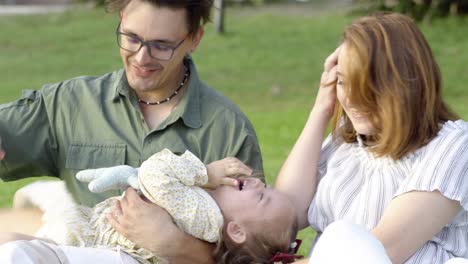 una joven familia feliz, padre y madre divirtiéndose con su alegre hija en el parque de la ciudad