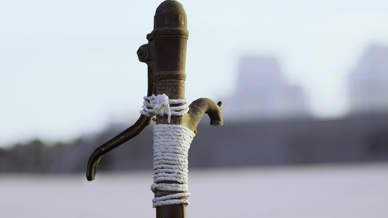 Old water pump stands resiliently against the backdrop of fading cityscapes