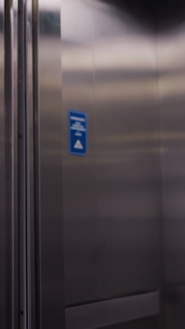 businesswoman walking out of elevator in modern office, smiling confidently. dressed in formal business suit, carrying a red handbag. clean, sleek elevator interior and professional environment