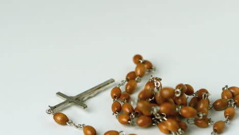 rosary beads falling on white surface