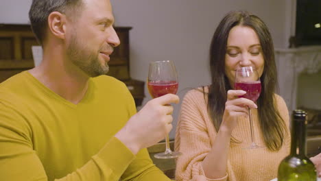 husband and wife talking and toasting during a family dinner sitting at table at home