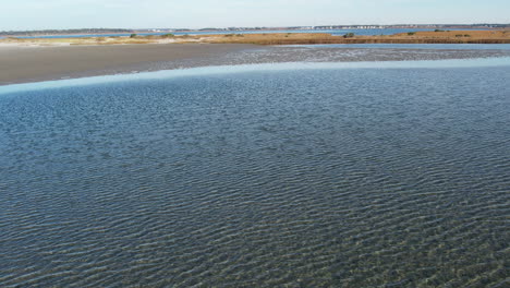 aerial shot of tidal flat with clear blue water and small island, coastal drone