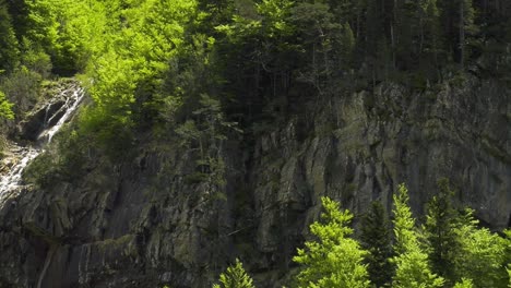 mountain rock face with cascading stream, panning shot