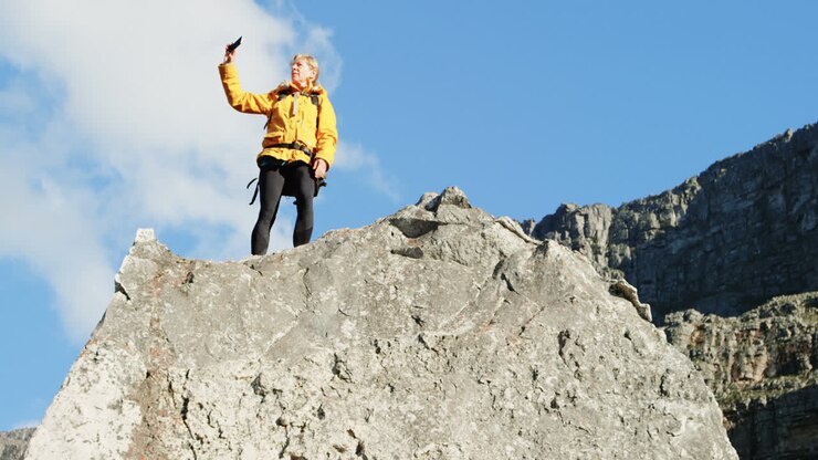 Donna anziana che si fa un selfie con il cellulare su una roccia 4k