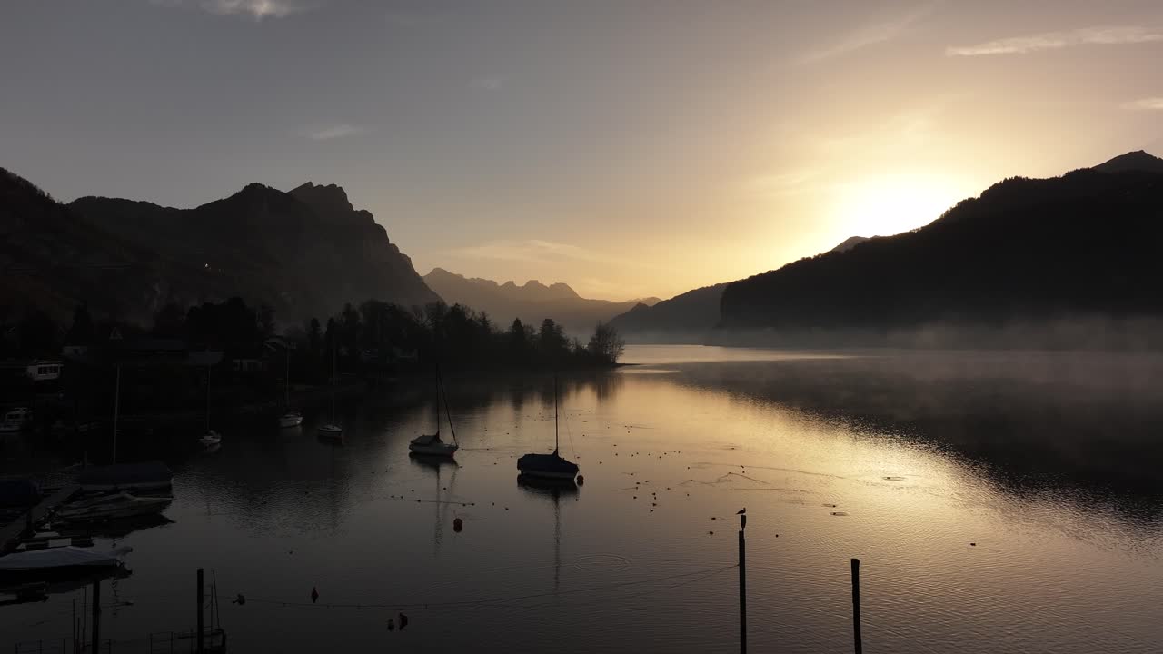 스위스의 발렌세 호수 (walensee lake) 에서 해가 뜨는 모습, 정박한 배와 산의 실루