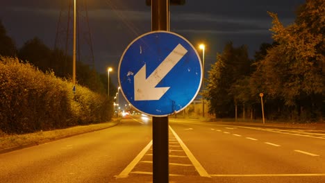 Vista-De-Cerca-De-Una-Señal-De-Tráfico-Con-Lapso-De-Tiempo-De-Movimiento-De-Vehículos-En-La-Calle-En-Dublín,-Irlanda-Por-La-Noche