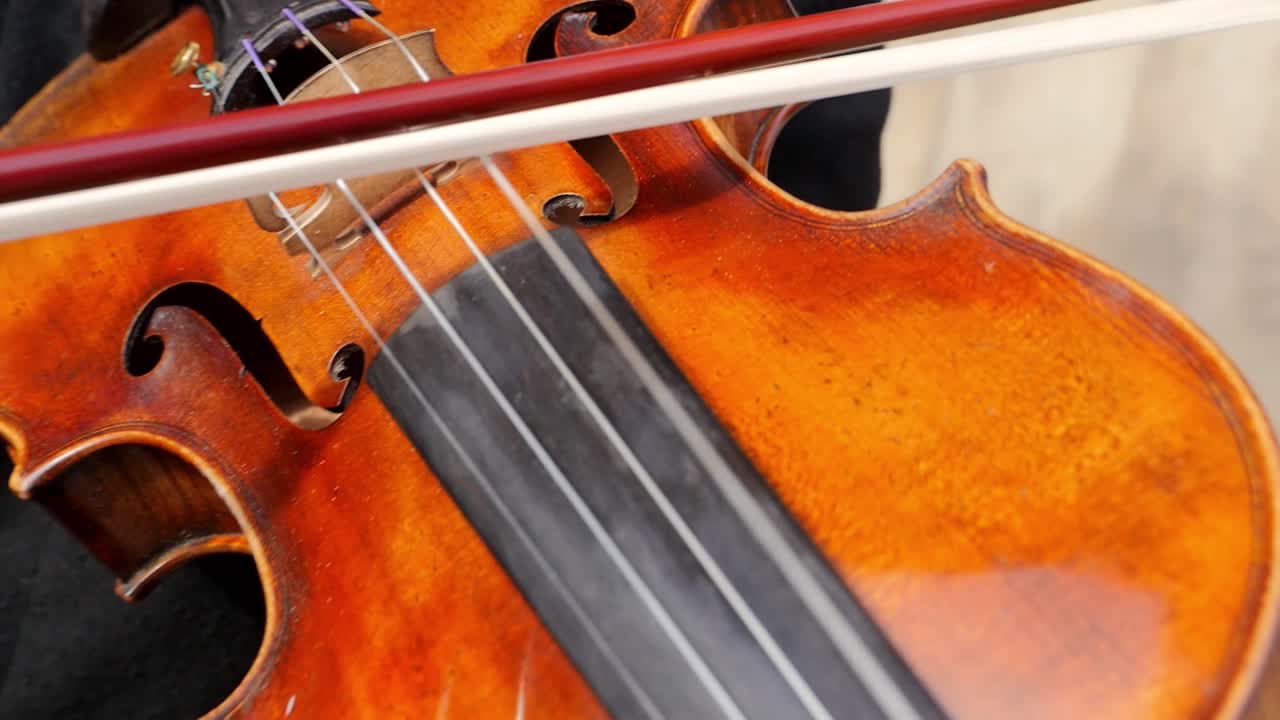 Close up shot of person playing violin instrument during sunny day in city