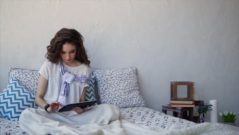 young woman using tablet on a bed