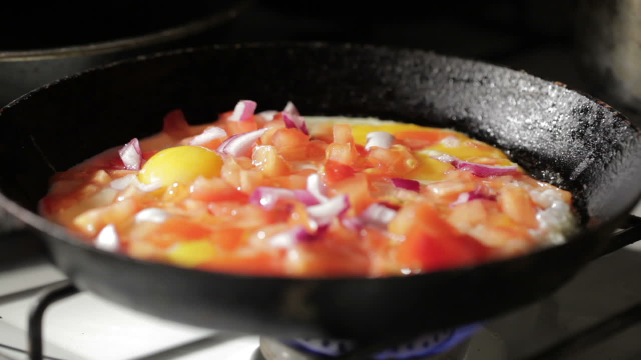Uovo che frigge in padella. Aggiunta di fette di cipolla.