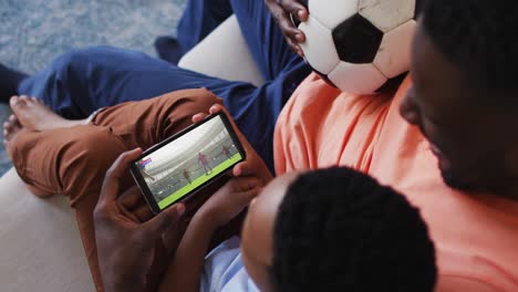 Compuesto-De-Padre-E-Hijo-En-Casa-Viendo-Un-Partido-De-Rugby-En-Un-Teléfono-Inteligente