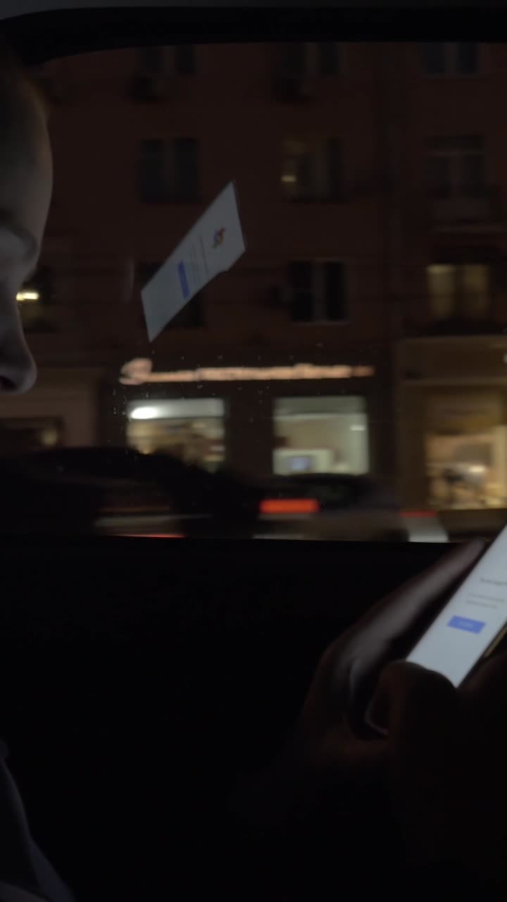Persona che usa lo smartphone mentre viaggia in auto di notte