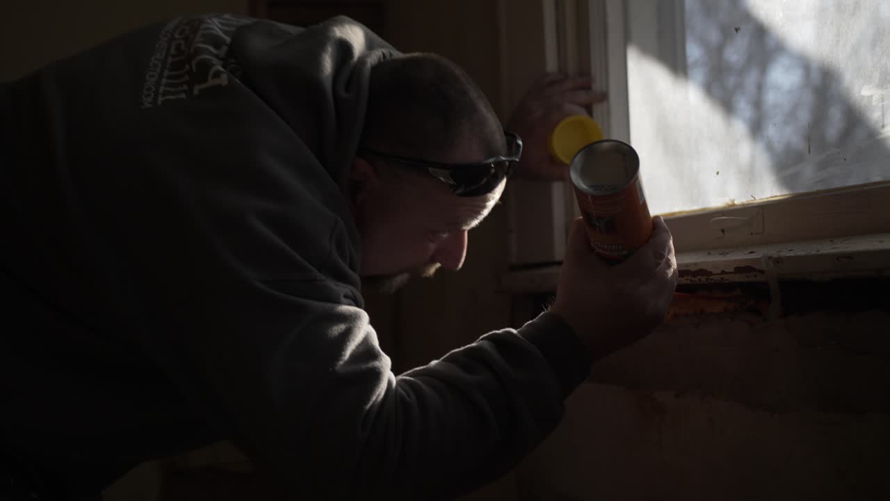 un hombre trabaja dentro de la remodelación de una casa - usa espuma en aerosol para aislar la ventana