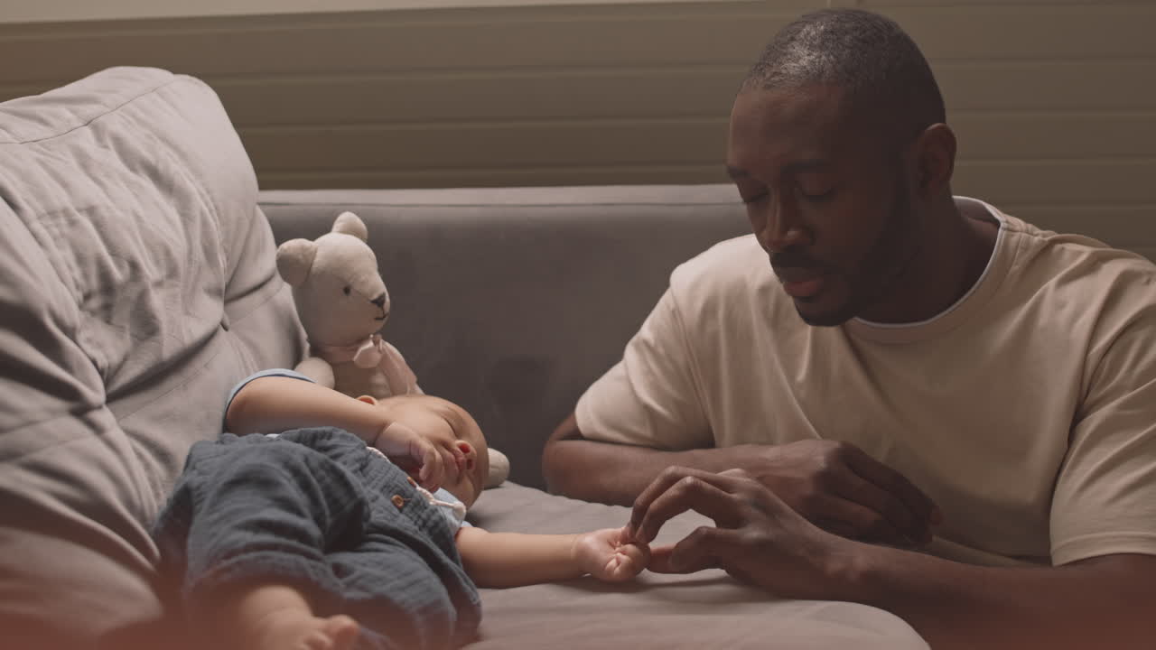 Father Touching Tiny Hand of Sleeping Baby