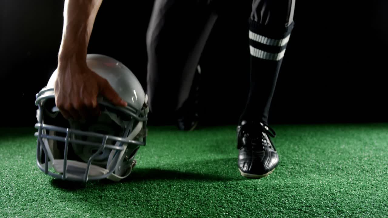 アメリカンフットボール選手がヘッドギアに手を置いている 4K