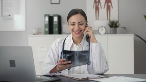 happy indian female doctor explaining x ray report to patient on call