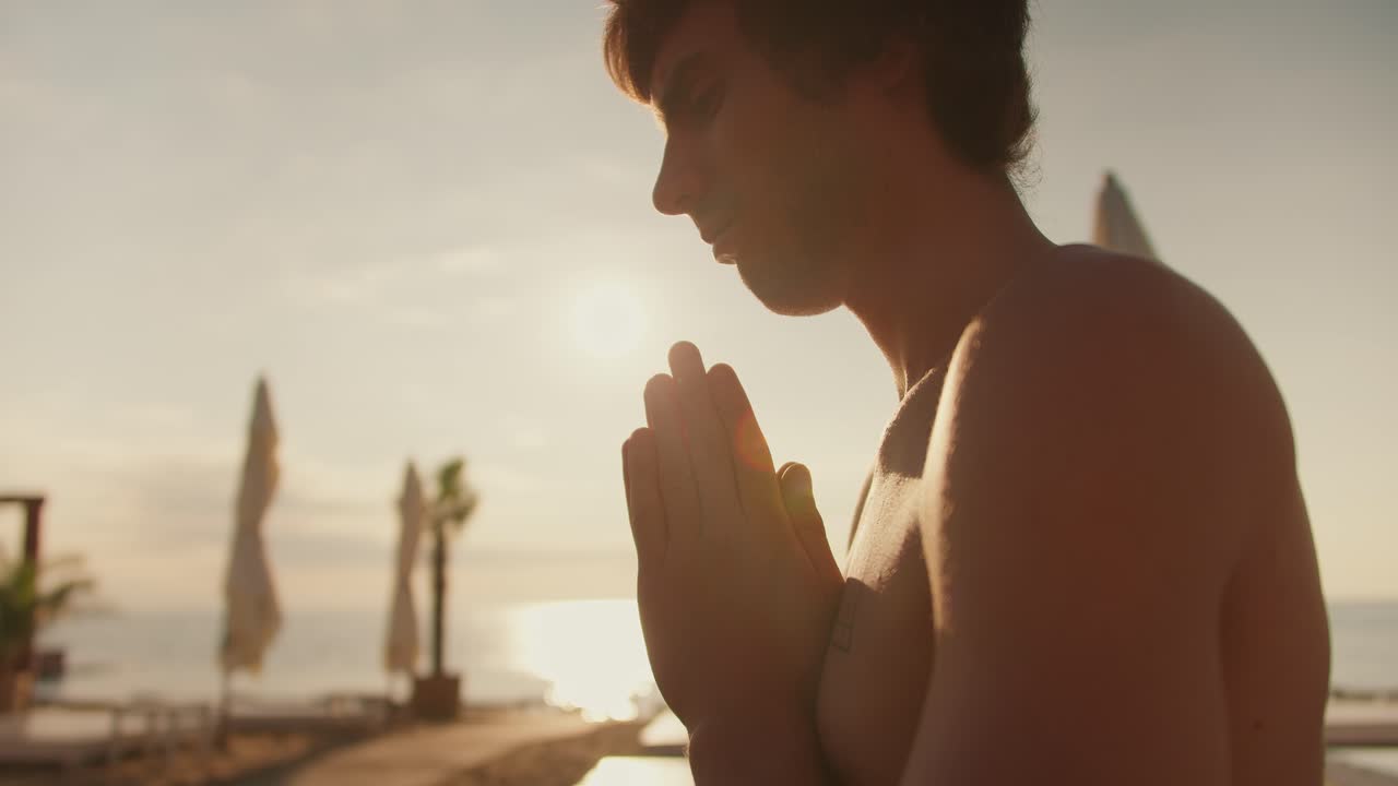 toma de primer plano: una vista de un tipo tranquilo meditando en la playa al amanecer. meditación matutina al aire libre