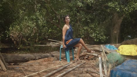 mujer feliz y bonita sentada en medio de la naturaleza mirando la cámara con los árboles balanceándose en el viento