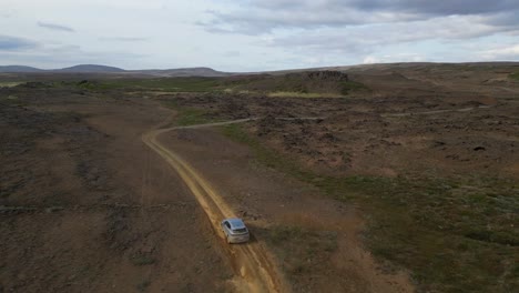 Aerial-view-from-car-driving-in-the-highlands-of-Iceland-during-summer-time,-surrounded-by-desert-roads-in-a-natural-path