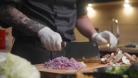 mushroom being sliced on a wooden board by professional chef in an elegant black shirt with tattoos and white gloves