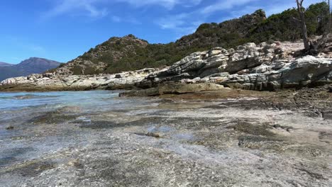 Tilt-up-view-of-Lotu-rocky-side-of-beach-in-summer-season,-Corsica-island-in-France