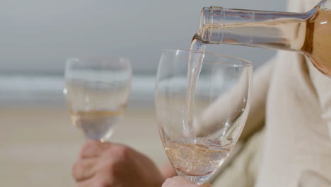 close up of an unrecognizable man pouring wine into glasses on the beach