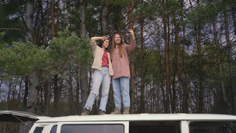 Zwei-Junge-Freundinnen-Machen-Ein-Selfie-Miteinander-Auf-Dem-Dach-Eines-Wohnwagens-Mitten-Im-Wald